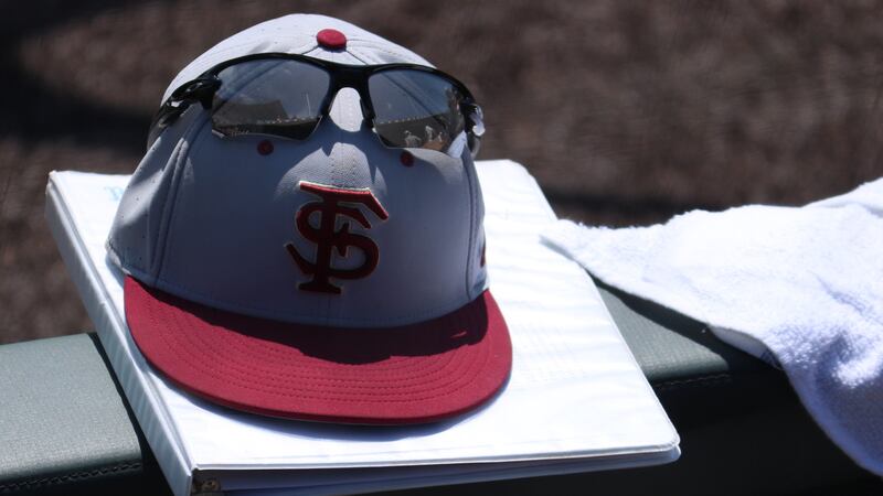 A Florida State Seminoles baseball cap hangs on the top railing of the dugout at the 2022...