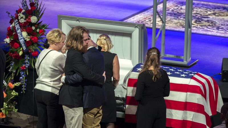 Dustin Walters, center left, hugs his brother Mason Walter, center right, during a funeral...