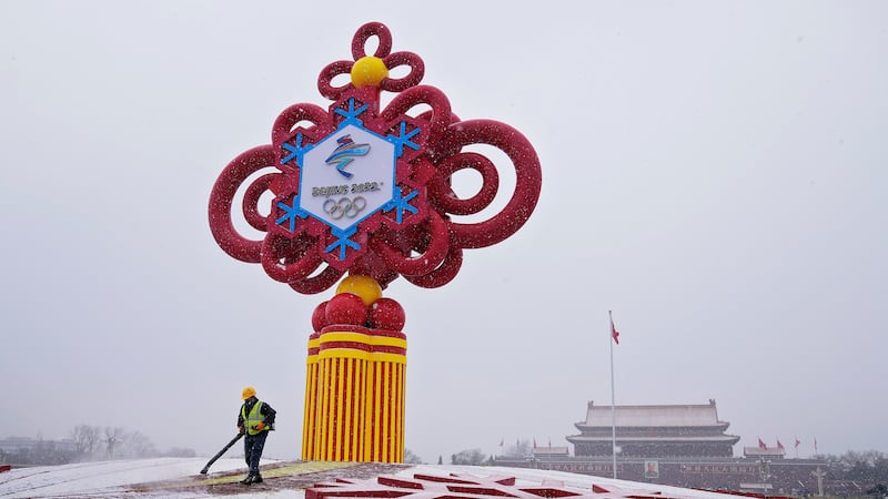 FILE - A worker wearing a face mask to protect from the coronavirus uses a blower to clean the...